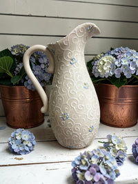 Decorative ceramic pitcher with bee patterns on a wooden surface with hydrangeas. Ladybird Ceramics Canada