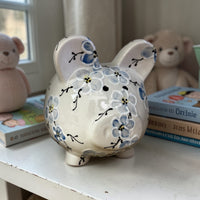 Blue Cherry Blossom floral Piggy bank with design on a surface with books and teddy bears in the background - Ladybird Ceramics 