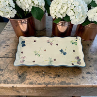 Decorative tray with blue accent and dragonfly patterns on a wooden surface with potted white flowers. Ladybird Ceramics Canada