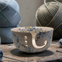 Decorative blue cherry blossom  ceramic yarn bowl with floral patterns on a wooden surface with yarn and knitting needles | Ladybird Ceramics Canada