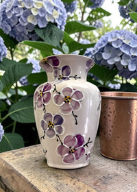 Vase with floral purple Cherry Blossom design in front of hydrangeas