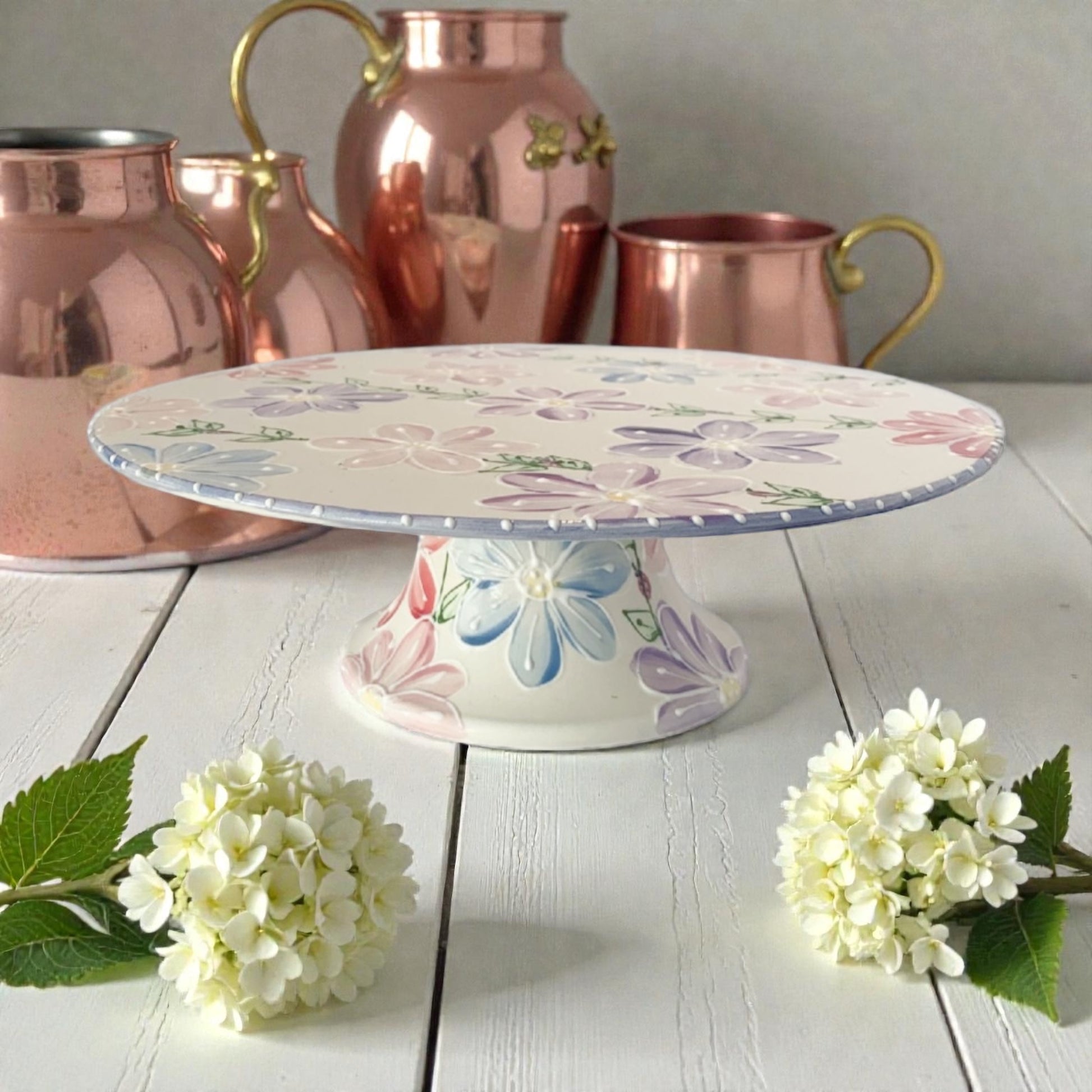 New Daisy Floral cake stand with copper pitchers in the background