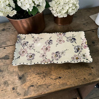 Floral-patterned ceramic tray with ruffle edge on a wooden surface with potted plants in the background Ladybird Ceramics Canada 