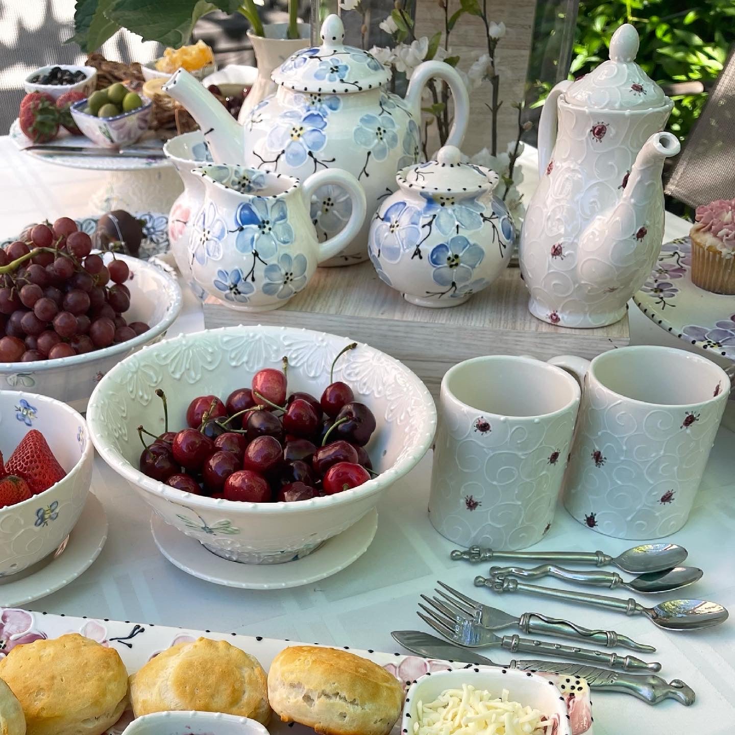 Tea set with floral patterns on a table with fruits and pastries