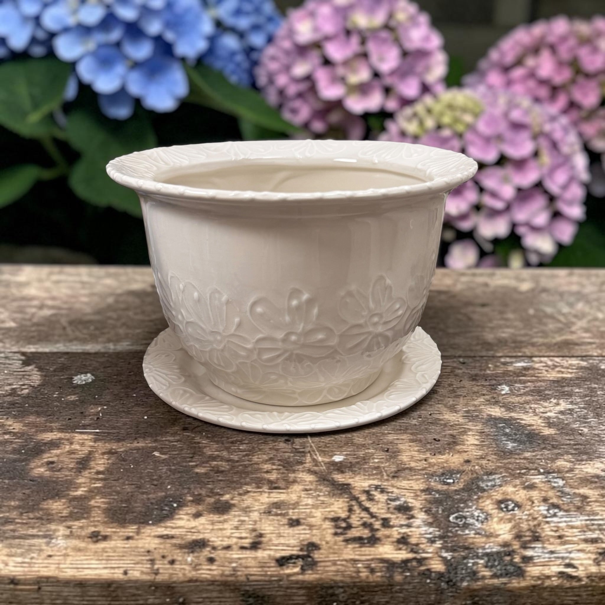 White decorative planter on a wooden surface with hydrangeas in the background | Ladybird Ceramics