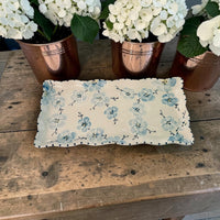 Floral-patterned blue cherry blossom hand painted ceramic tray  on a wooden surface with potted plants in the background