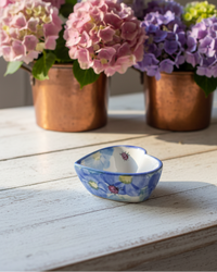Three copper pots with hydrangea flowers on a wooden surface.