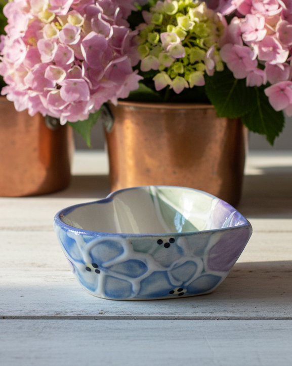 Decorative ceramic bowl with floral patterns on a wooden surface with pink flowers in the background.
